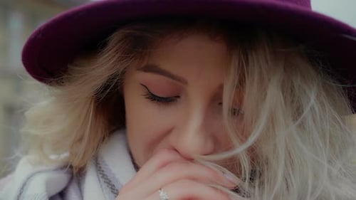 Young woman warms her hands dressed in warm clothes.