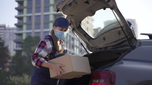 Masked Delivery Woman Taking Boxes From Car Trunk