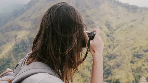 Woman Taking Pictures in a Mountainous Landscape