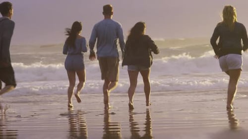 Group of friends at beach running in surf