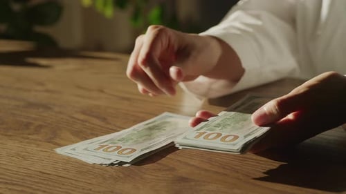 Handheld Close Up of Caucasian Woman Hands Counting Money in 100 Dollar Bills
