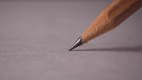 Pencil Draws Line on Gray Paper Close Up