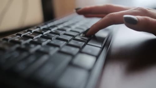 Seitenansicht einer afrikanischen Geschäftsfrau im Kleid, die auf einem Sessel neben dem Fenster sitzt und Laptop benutzt