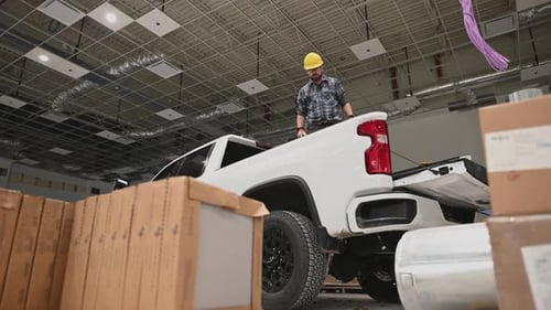 Trabajador con casco amarillo saltando de su camioneta