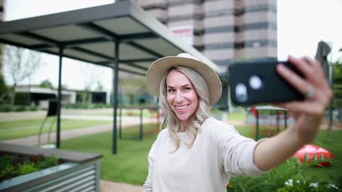 Smiling Woman Taking Selfie in Urban Park
