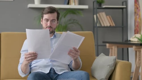 Man Reading Documents at Home on the Couch