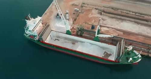 Vista aérea. El barco llegó al puerto. Descarga de un buque de carga mediante una excavadora dentro del
barco