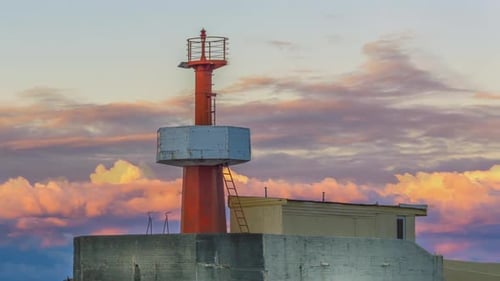 Ein wunderschöner Leuchtturm in einer Meereslandschaft, in der die Sonnenuntergangswolken wie ein Zeitraffer belebt sind, aber der