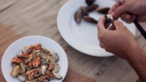 Man Prepares Mussels with Knife on Table