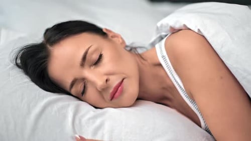 Dark Haired Woman Sleeping Peacefully in White Bed