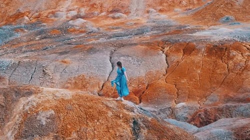 Woman Posing in Teal Dress on Rocky Landscape