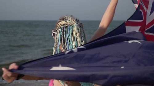 Woman Smiling and Holding Flag on Beach