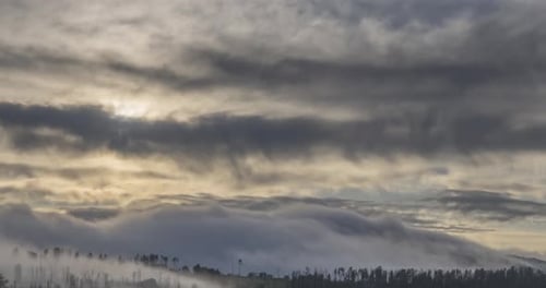 Zeitraffer der abendlichen Sonnenstrahlen, die durch die kalten, nebligen Wolken in den Bergen auftauchen