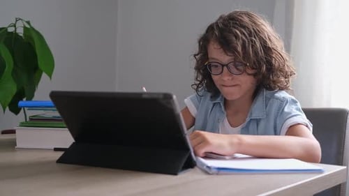 Little Adorable School Boy with Eyeglasses Studying Online From Home