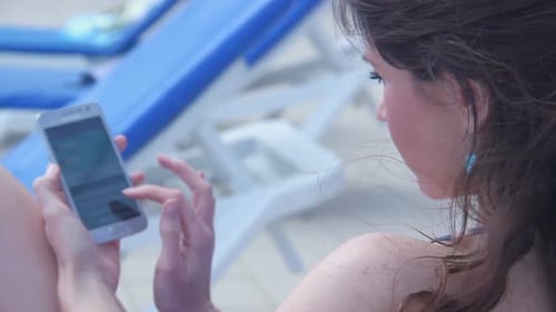 Woman Using Smartphone Relaxing on Beach Lounge Chair