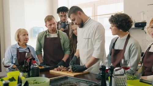 Zeitlupe von Menschen, die dem Koch beim Kochen einer Mahlzeit während des Kochkurses zusehen