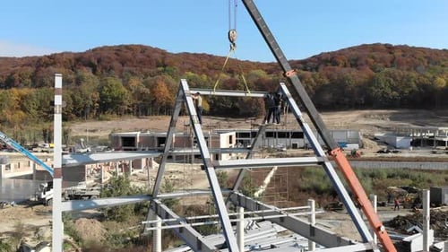 Luftaufnahme: Installation eines Daches und eines Rahmens aus einer Metallkonstruktion. Arbeiter montieren das Dach
