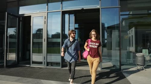 Young Adults Walking Out Of Glass Building