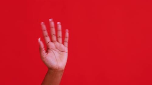 Hand Gesturing Thumbs Up Against Red Background