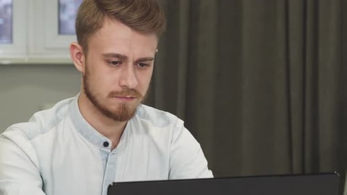 Smiling Man Uses Laptop in Natural Light