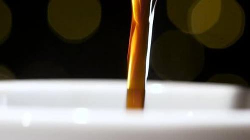 Closeup. Pouring Jet of Black Coffee in a White Cup