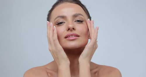 Woman Demonstrate Moisturizing Facial Care Touching Cheek Isolated on Gray Studio Background