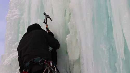 Ice Climber Ascending Frozen Waterfall in Winter