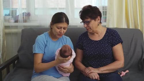 Mother and Grandmother Admire Newborn Baby