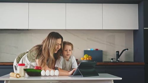 Woman and Child Looking at Tablet in Kitchen
