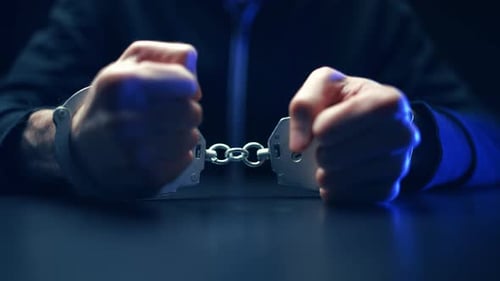 Man in Handcuffs on a Dark Table