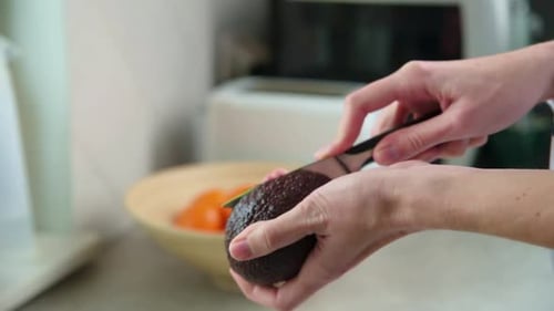 Cutting Avocado In Half In Bright Kitchen