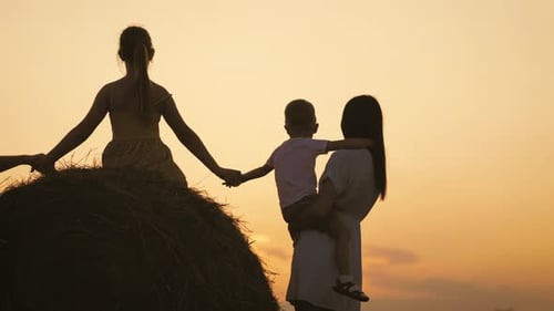 Family Silhouette on Hay Bale at Sunset