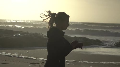 Woman Jogging on Beach at Sunset
