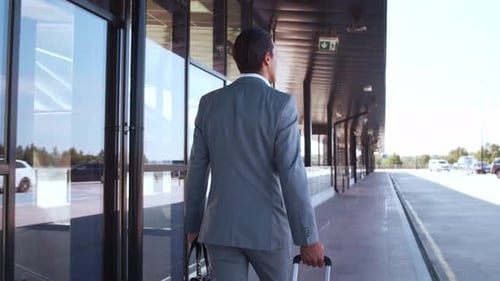 Elegant businessman walking with suitcase along the airport. Young mail entrepreneur.