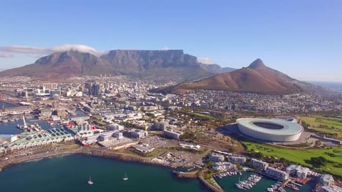 Aerial travel drone view of Cape Town, South Africa with Table Mountain and stadium.