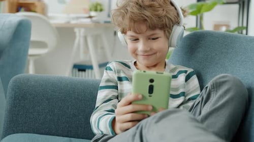 Boy With Headphones Using Smartphone on Couch