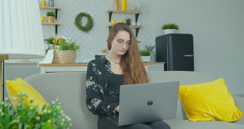 Woman Working on Laptop on Couch at Home