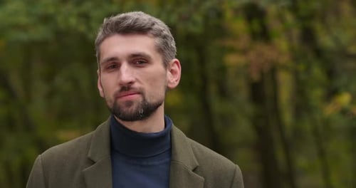 Visage rapproché d'un bel homme caucasien aux cheveux gris souriant aux yeux bruns debout dans la forêt et