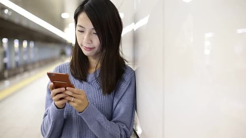 Woman texting message on cellphone at subway station