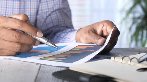 Menschenhand mit Stift Analysieren von Balkendiagramm auf Papier