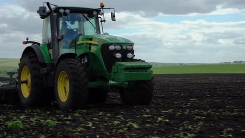Tractor plows the ground with a plow in the field