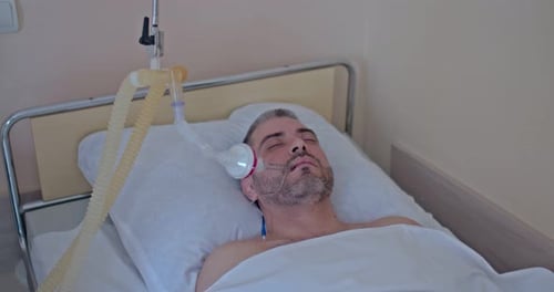 Man Lying in Hospital Bed with Equipment