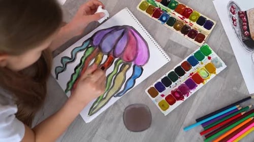 Girl Paints Jellyfish with Watercolor on Paper at Home