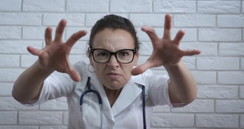 Angry Doctor Reaches Towards Camera with Spreading Fingers