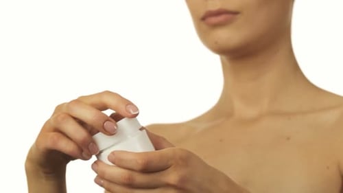 Young Adult Opens Container of Beauty Cream