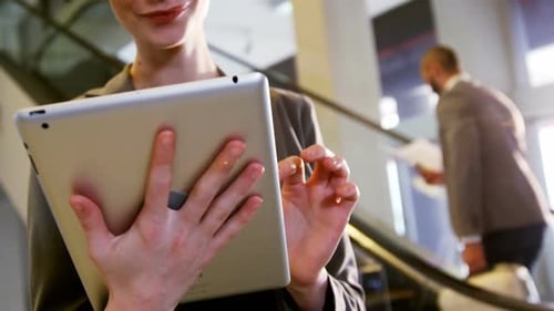 Woman Using Tablet on Escalator at Business Center