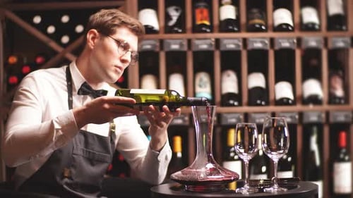 Sommelier qualifié versant le vin de la carafe dans un verre à vin.