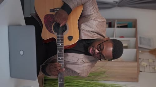 Man Plays Guitar at Desk