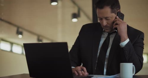 Man Working on Laptop While on Phone Call