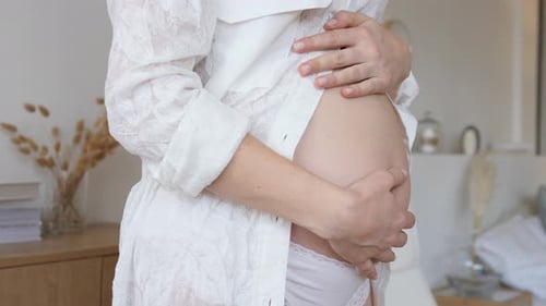 Pregnant Woman Holding her Baby Bump Indoors